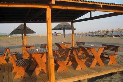 a group of tables and chairs with umbrellas on a beach at Villa Elkom, App.11 in Donji Štoj
