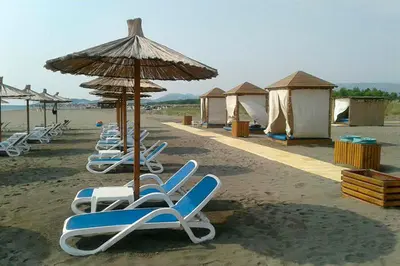 a row of lounge chairs and an umbrella on the beach at Villa Elkom, App.9 in Ulcinj