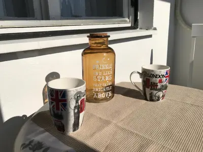 a table with two mugs and a bottle on it at SunFlat Podgorica - Novakovic Residence in Podgorica