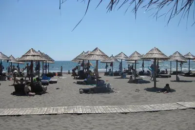 a group of people laying on a beach with umbrellas at Villa Elkom, App.3 in Ulcinj