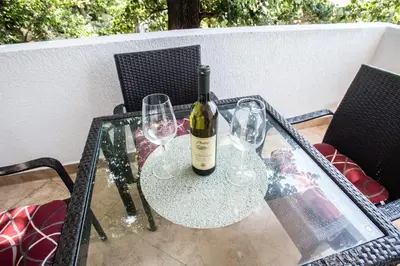 a glass table with a bottle of wine and two glasses at Villa Elkom, App.4 in Ulcinj