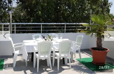 a white table with white chairs and a potted plant at Villa Elkom, App.4 in Ulcinj