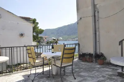 a table and chairs on a balcony with a view of the water at Apartments Vujošević in Kotor