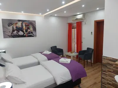 a bedroom with two beds and a painting on the wall at Apartments Nancy in Kotor