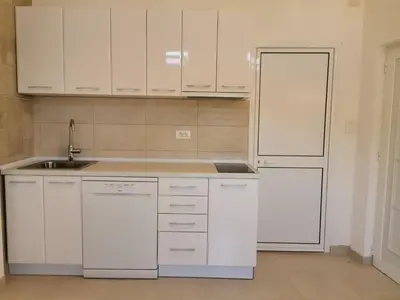 a kitchen with white cabinets and a sink and a refrigerator at STUDIO Carpe Diem in Utjeha