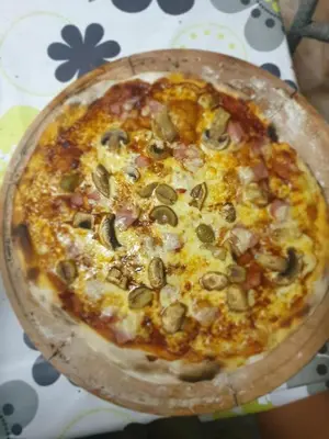 a pizza sitting on top of a wooden plate at STUDIO Carpe Diem in Utjeha