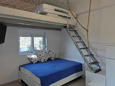 a bedroom with a bed with a ladder on the wall at STUDIO Carpe Diem in Utjeha