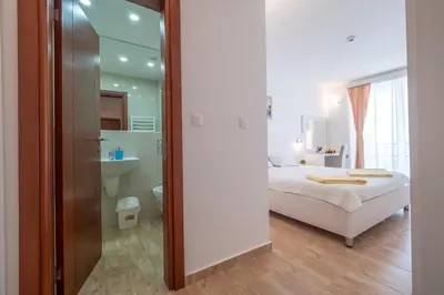 a bedroom with a white bed and a bathroom at Villa Skyprime in Budva