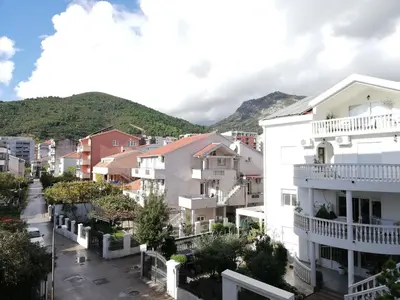 a city street with houses and mountains in the background at Apartment Azalea of Budva in Budva