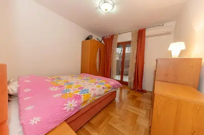 a bedroom with a pink bed with flowers on it at Apartment Qservice Petrovac in Budva