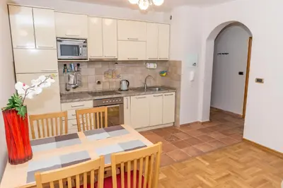 a kitchen with a dining table and a kitchen with white cabinets at Apartment Qservice Petrovac in Budva