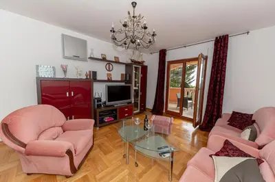 a living room with pink furniture and a chandelier at Apartment Qservice Petrovac in Budva