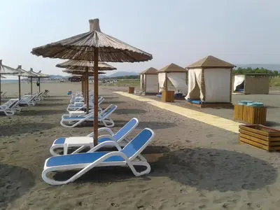 a row of lounge chairs and an umbrella on a beach at Villa Elkom, App 14 in Ulcinj