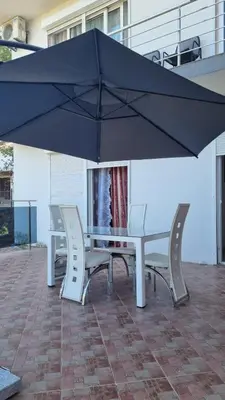 a table and chairs under an umbrella on a patio at Villa Alisa in Dobra Voda
