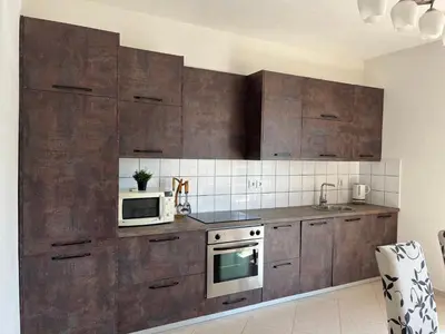 a kitchen with wooden cabinets and a microwave at Villa Alisa in Dobra Voda