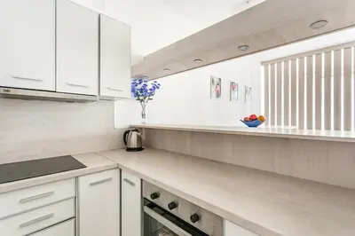 a white kitchen with white cabinets and a window at Apartments BEATRICE Rafailovici in Rafailovici