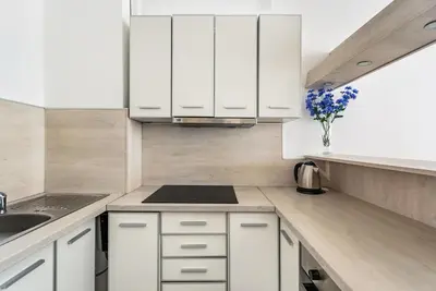 a kitchen with white cabinets and a vase of flowers at Apartments BEATRICE Rafailovici in Rafailovici