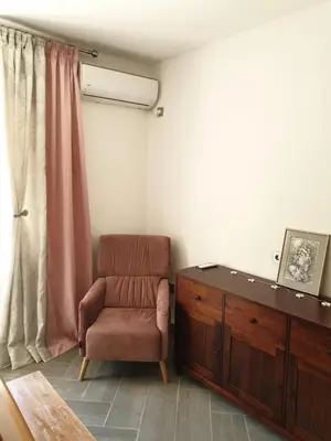 a living room with a chair and a dresser at Апартаменты Anturage с отдельным входом in Dobra Voda