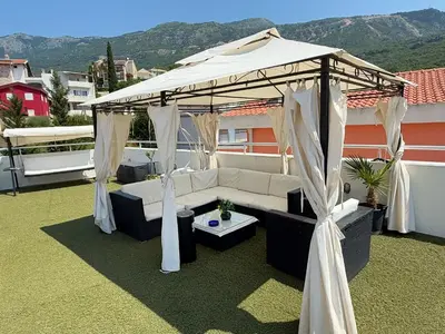 a couch under a gazebo on a roof at Apartmani Avanti Becici in Becici