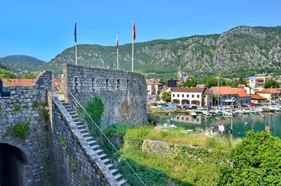 a city with a castle and a harbor with boats at Bright, Romantic & Super Stylish Old Town Flat with Seaview & Shared Terrace in Kotor