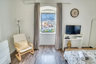 a bedroom with a bed and a chair and a window at Bright, Romantic & Super Stylish Old Town Flat with Seaview & Shared Terrace in Kotor