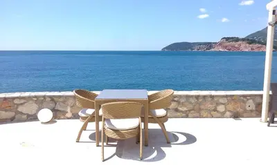a table and chairs on a balcony overlooking the ocean at Love Live Hotel in Sutomore