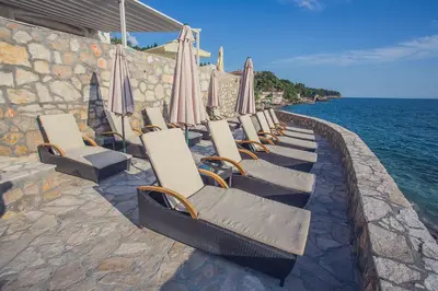 a row of chairs with umbrellas and the ocean at Love Live Hotel in Sutomore