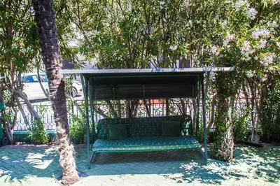 a green bench sitting under a canopy under trees at Villa Elkom, App 16 in Ulcinj