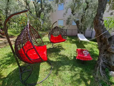 two swings in a yard next to a tree at Palm Point Apartment in Petrovac na Moru