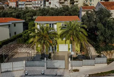 a yellow house with palm trees in front of it at Palm Point Apartment in Petrovac na Moru
