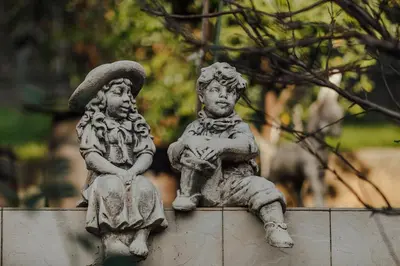 a statue of two people sitting on a wall at Palm Point Apartment in Petrovac na Moru
