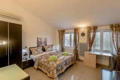 a bedroom with a bed and a desk and windows at Olive Garden Apartment in Petrovac na Moru