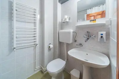 a white bathroom with a toilet and a sink at R club Apartments Old Town Budva in Budva