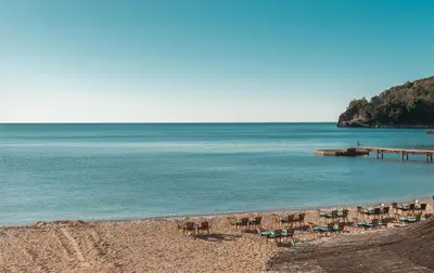 a beach with chairs and a pier in the water at R club Apartments Old Town Budva in Budva