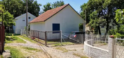 a small white house with a fence in front of it at Forest house in Sutomore