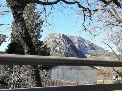 a mountain in the distance with a tree and a fence at Forest house in Sutomore