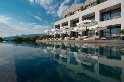 a pool of water with umbrellas and a building at Vivid Blue Serenity Resort in Sveti Stefan