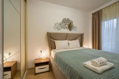 a bedroom with a bed with a green blanket and a mirror at Montesun Boka Apartments in Budva