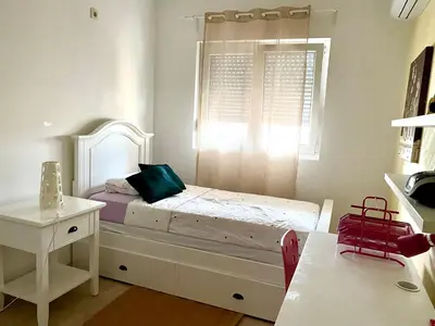 a small bedroom with a white bed and a window at City Apartment in Podgorica