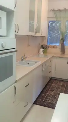 a kitchen with white cabinets and a sink at City Apartment in Podgorica