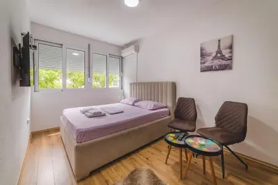 a small bedroom with a bed and two chairs at Top-Top in Podgorica
