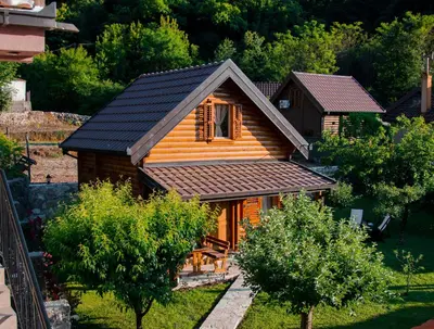 a small wooden house with a black roof at Green Field Apartments in Virpazar