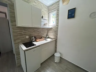 a small kitchen with white cabinets and a sink at Green Field Apartments in Virpazar