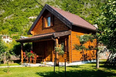 a log cabin with a window and flowers in the yard at Green Field Apartments in Virpazar
