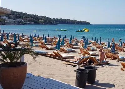 a beach with people sitting in chairs and umbrellas at Villa Jovanovic Sutomore in Sutomore