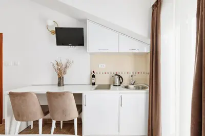 a kitchen with white cabinets and a sink and two chairs at Apartments Rozer in Kotor