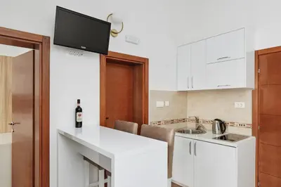 a kitchen with white cabinets and a tv on the wall at Apartments Rozer in Kotor