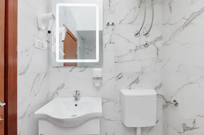 a white bathroom with a sink and a mirror at Apartments Rozer in Kotor