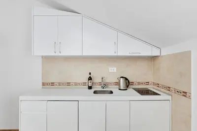 a white kitchen with white cabinets and a sink at Apartments Rozer in Kotor