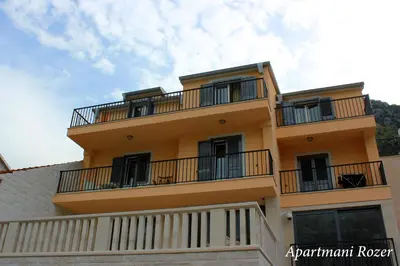 a yellow building with balconies on top of it at Apartments Rozer in Kotor